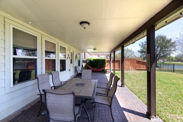 view of patio with fence, outdoor dining space, and a water view