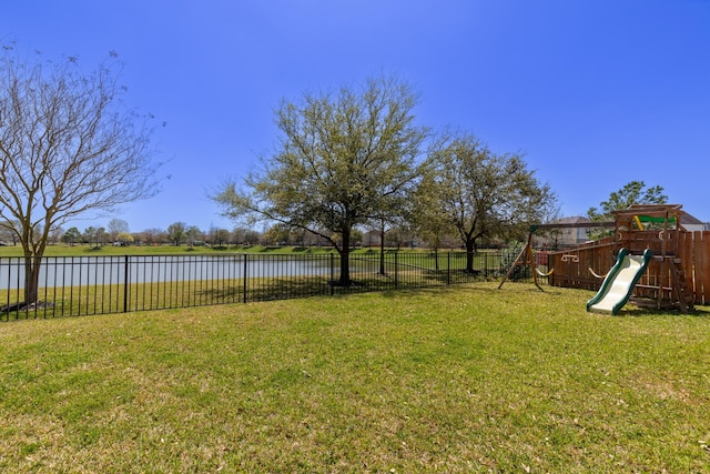 view of yard with a water view, a playground, and fence