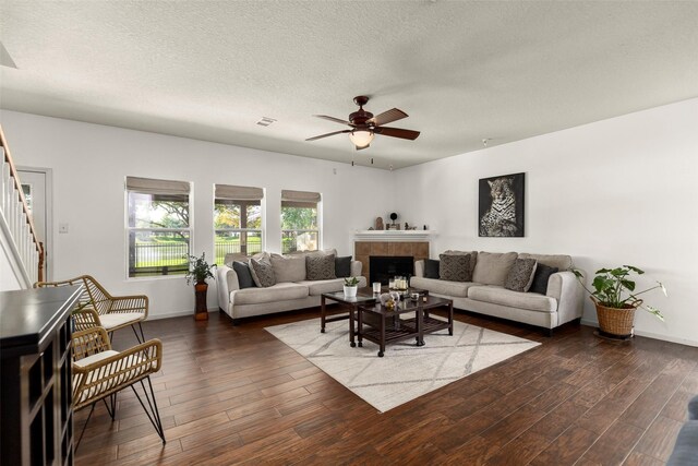 19527 Hardwood Ridge Trl, Cypress, TX 77429 - living area featuring stairs, a ceiling fan, dark wood-style floors, a tile fireplace, and a textured ceiling