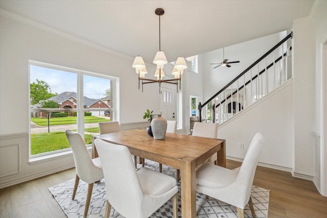 dining area with light wood-style floors, stairs, and ceiling fan with notable chandelier