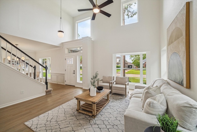 living room featuring ceiling fan, stairs, wood finished floors, and a wealth of natural light