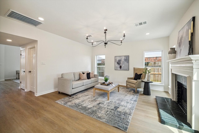 living area with visible vents, an inviting chandelier, and light wood-type flooring