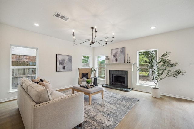 living area with baseboards, a notable chandelier, wood finished floors, and a wealth of natural light