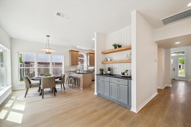 kitchen featuring light wood-style floors, dark countertops, open shelves, and visible vents