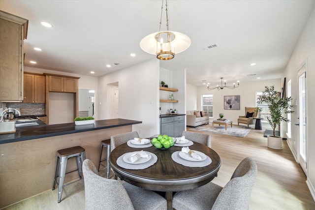 dining room featuring visible vents, a healthy amount of sunlight, an inviting chandelier, and light wood finished floors