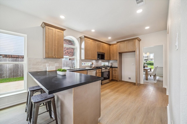 kitchen featuring visible vents, dark countertops, a peninsula, stainless steel appliances, and a wealth of natural light