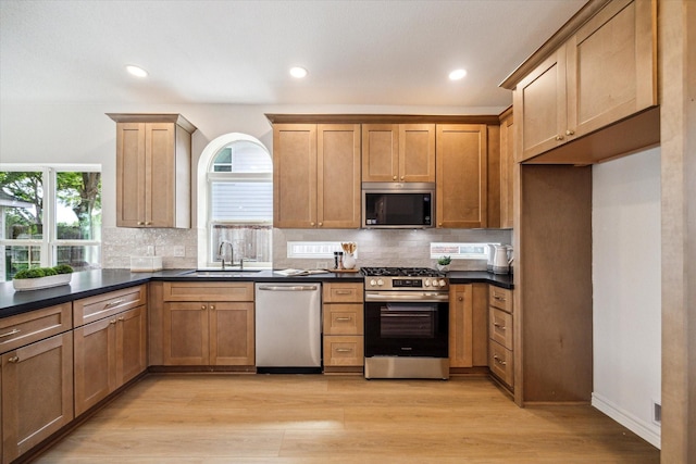 kitchen with dark countertops, appliances with stainless steel finishes, decorative backsplash, and a sink