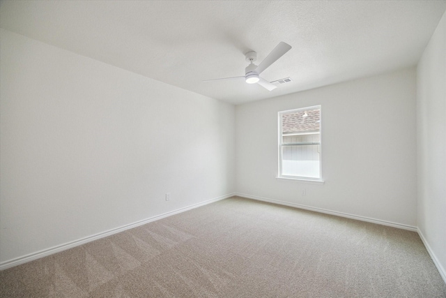 empty room with carpet floors, ceiling fan, baseboards, and visible vents