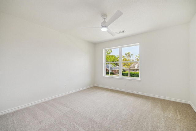 empty room featuring visible vents, a ceiling fan, baseboards, and light carpet