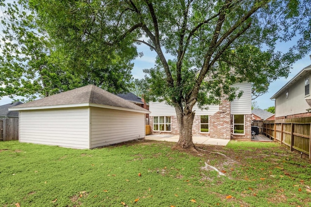 back of house featuring a fenced backyard, a patio, a yard, and brick siding