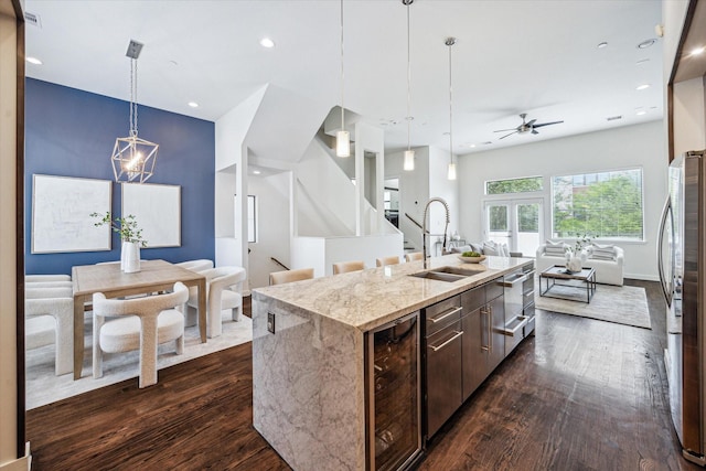 kitchen with freestanding refrigerator, beverage cooler, open floor plan, a center island with sink, and a sink