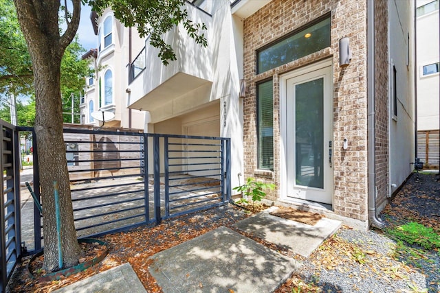 entrance to property featuring brick siding, fence, and a gate