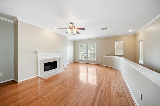 unfurnished living room featuring visible vents, crown molding, wood finished floors, ceiling fan, and a tiled fireplace