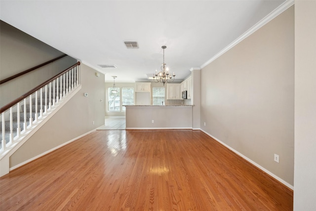 unfurnished living room with visible vents, stairway, an inviting chandelier, ornamental molding, and light wood-style flooring