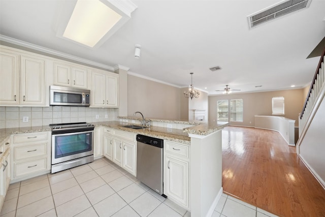 kitchen with visible vents, crown molding, a sink, a peninsula, and stainless steel appliances