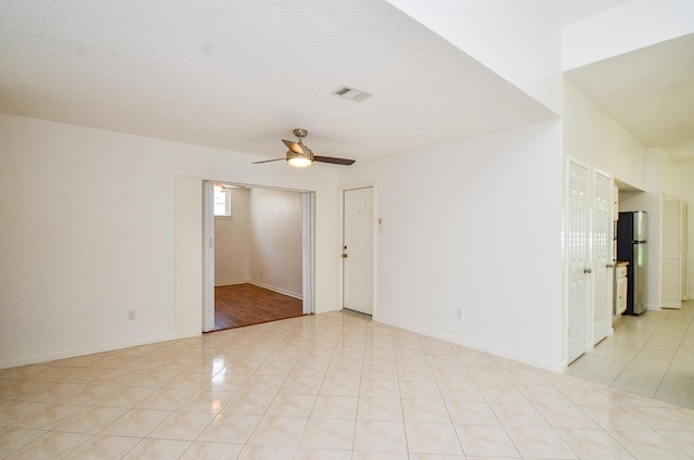 spare room with visible vents, ceiling fan, and light tile patterned floors