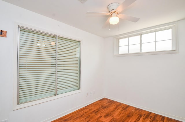 empty room with baseboards, a ceiling fan, and dark wood-type flooring