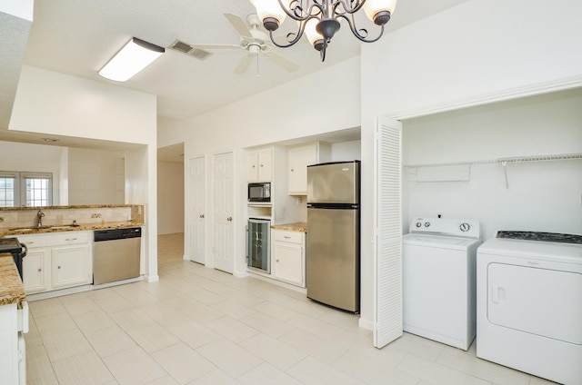 kitchen featuring a sink, black appliances, ceiling fan with notable chandelier, beverage cooler, and washer and dryer
