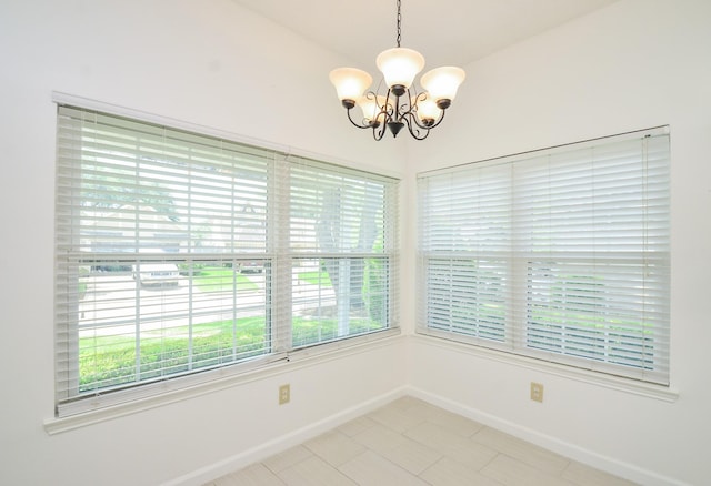 unfurnished room with baseboards, an inviting chandelier, and a healthy amount of sunlight