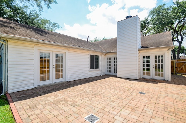 back of house featuring a patio area, roof with shingles, french doors, and a chimney