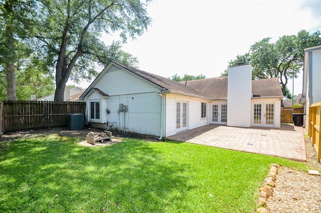 back of property featuring a patio, a fenced backyard, french doors, a chimney, and a yard