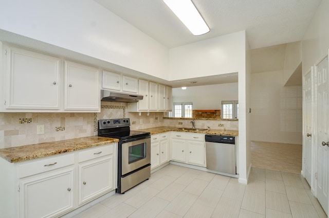 kitchen featuring decorative backsplash, appliances with stainless steel finishes, light stone countertops, a sink, and under cabinet range hood