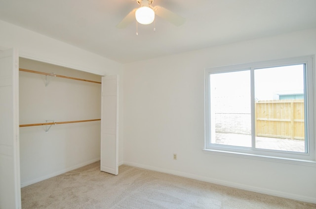 unfurnished bedroom featuring baseboards, multiple windows, a closet, and light colored carpet