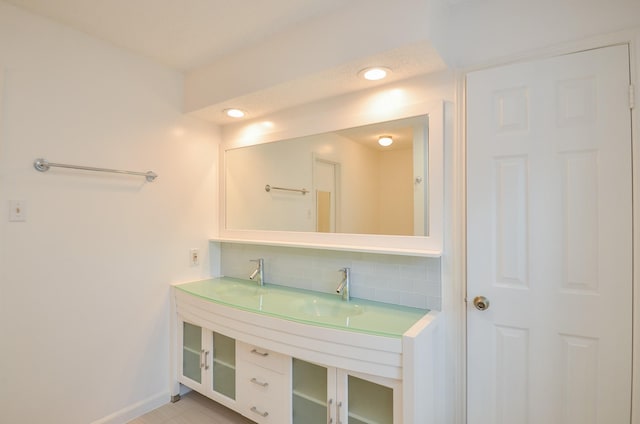 bathroom featuring backsplash, baseboards, and a sink