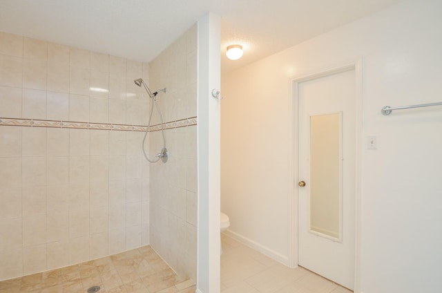 bathroom with toilet, tiled shower, and tile patterned flooring