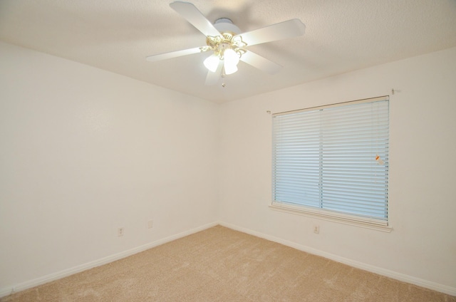 spare room featuring a ceiling fan, baseboards, and light carpet