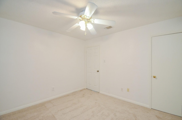 unfurnished room with baseboards, a ceiling fan, light colored carpet, and visible vents
