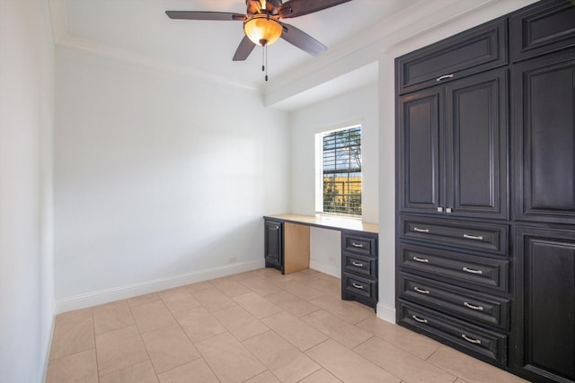 unfurnished office featuring light tile patterned floors, ceiling fan, baseboards, and built in study area