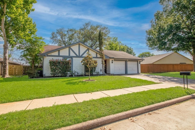 tudor home featuring an attached garage, a front lawn, fence, and driveway