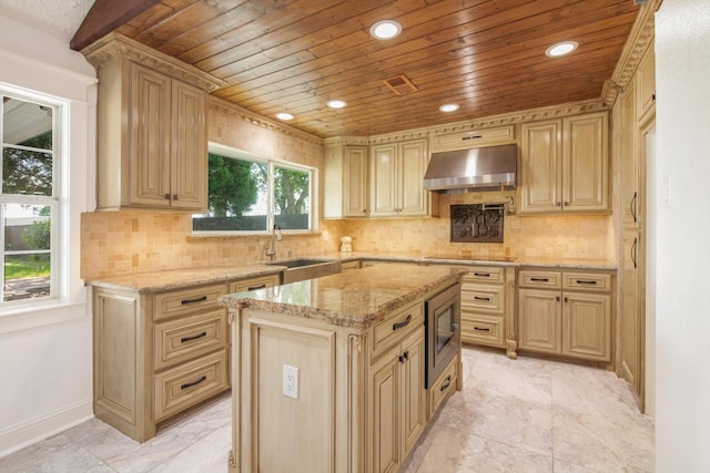 kitchen featuring wall chimney range hood, light stone counters, a sink, wooden ceiling, and backsplash