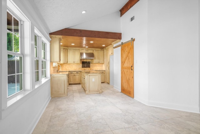 kitchen featuring a kitchen island, vaulted ceiling, a sink, baseboards, and under cabinet range hood