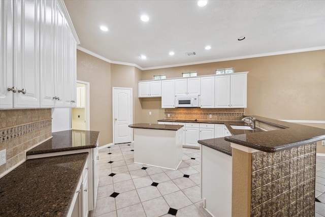 kitchen with a sink, recessed lighting, white microwave, backsplash, and visible vents