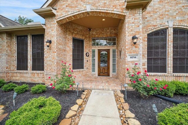doorway to property with covered porch and brick siding