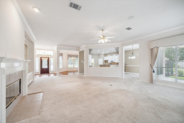 unfurnished living room featuring visible vents, ornamental molding, light carpet, and a tile fireplace