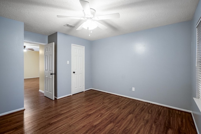 unfurnished bedroom with a textured ceiling, baseboards, dark wood-style floors, and visible vents