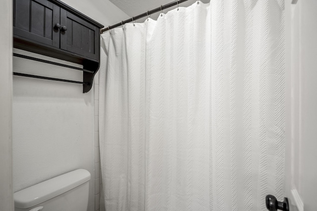 bathroom with toilet and a shower with curtain