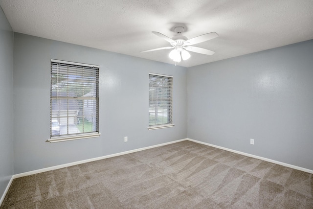 carpeted spare room featuring ceiling fan, a wealth of natural light, and baseboards