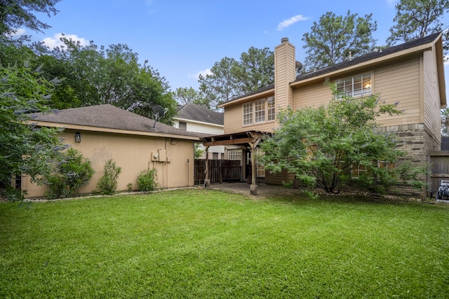 back of property with a yard, a chimney, fence, and a patio