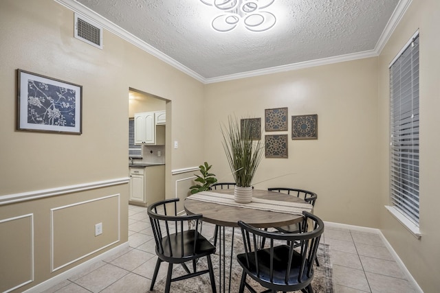 dining area featuring light tile patterned floors, ornamental molding, visible vents, and a textured ceiling