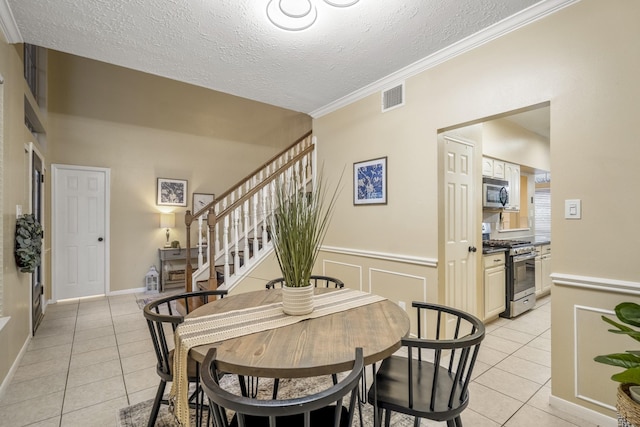 dining area with stairway, a textured ceiling, light tile patterned floors, and visible vents