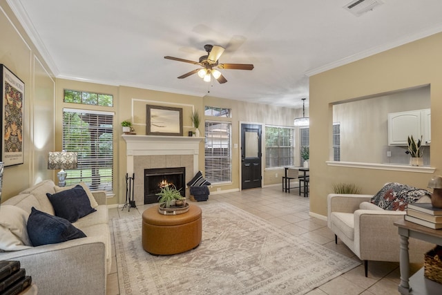 tiled living room featuring baseboards, ceiling fan, visible vents, crown molding, and a fireplace