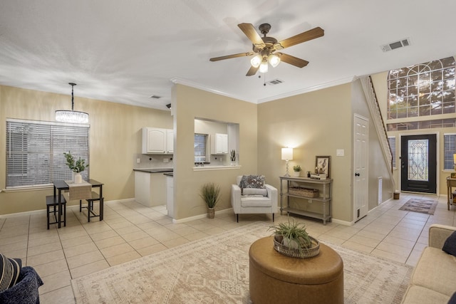 living room with light tile patterned floors, visible vents, baseboards, and ceiling fan with notable chandelier