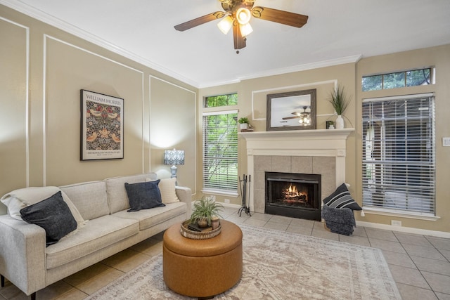 tiled living area featuring ceiling fan, crown molding, a healthy amount of sunlight, and a tile fireplace