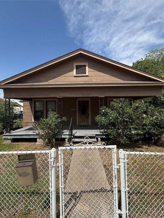bungalow-style house with covered porch, a fenced front yard, and a gate