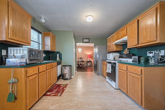 10834 Glenora Dr, Houston, TX 77065 - kitchen with dark countertops, a textured ceiling, under cabinet range hood, brown cabinets, and appliances with stainless steel finishes