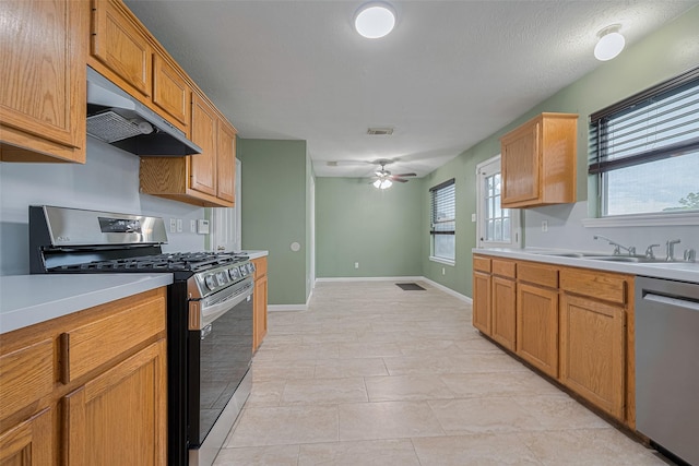 10834 Glenora Dr, Houston, TX 77065 - kitchen featuring appliances with stainless steel finishes, under cabinet range hood, light countertops, ceiling fan, and brown cabinetry